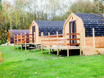 A series of camping cabins facing away from a hill in a forest setting.