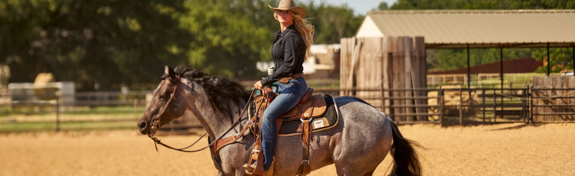Woman in a cowboy hat riding a horse in the ring
