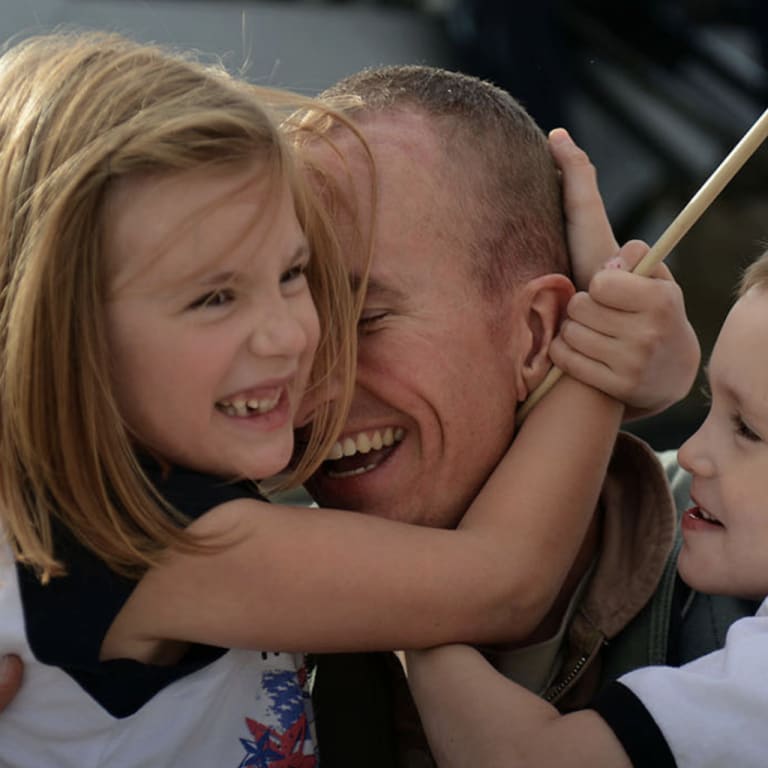 Man hugging his daughter and son with American flag