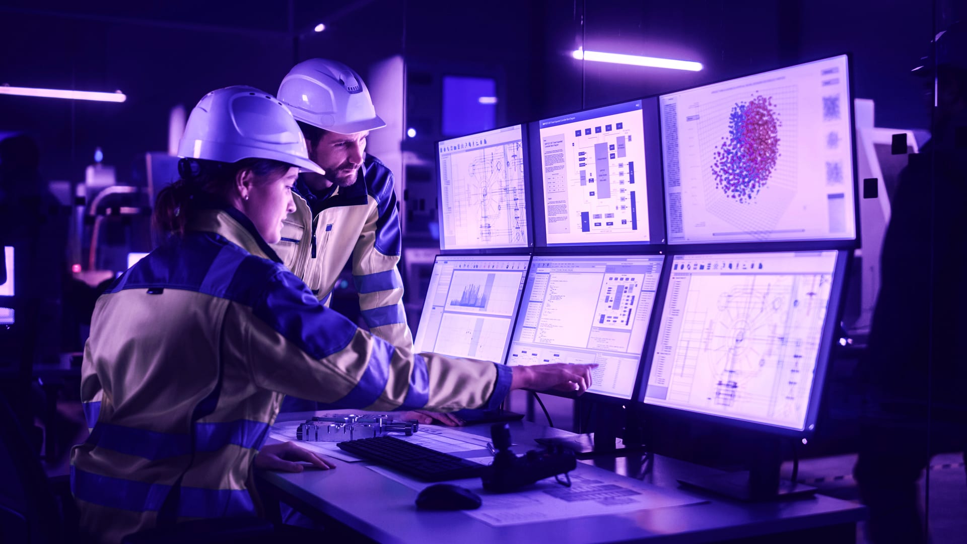 two industrial workers looking at monitors in a factory