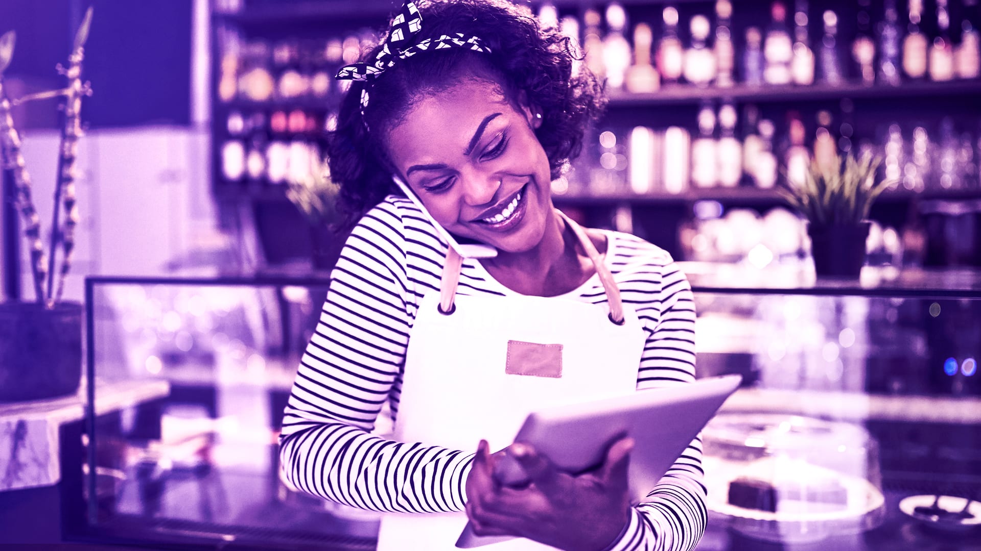 retail cafe worker talking on phone using a tablet