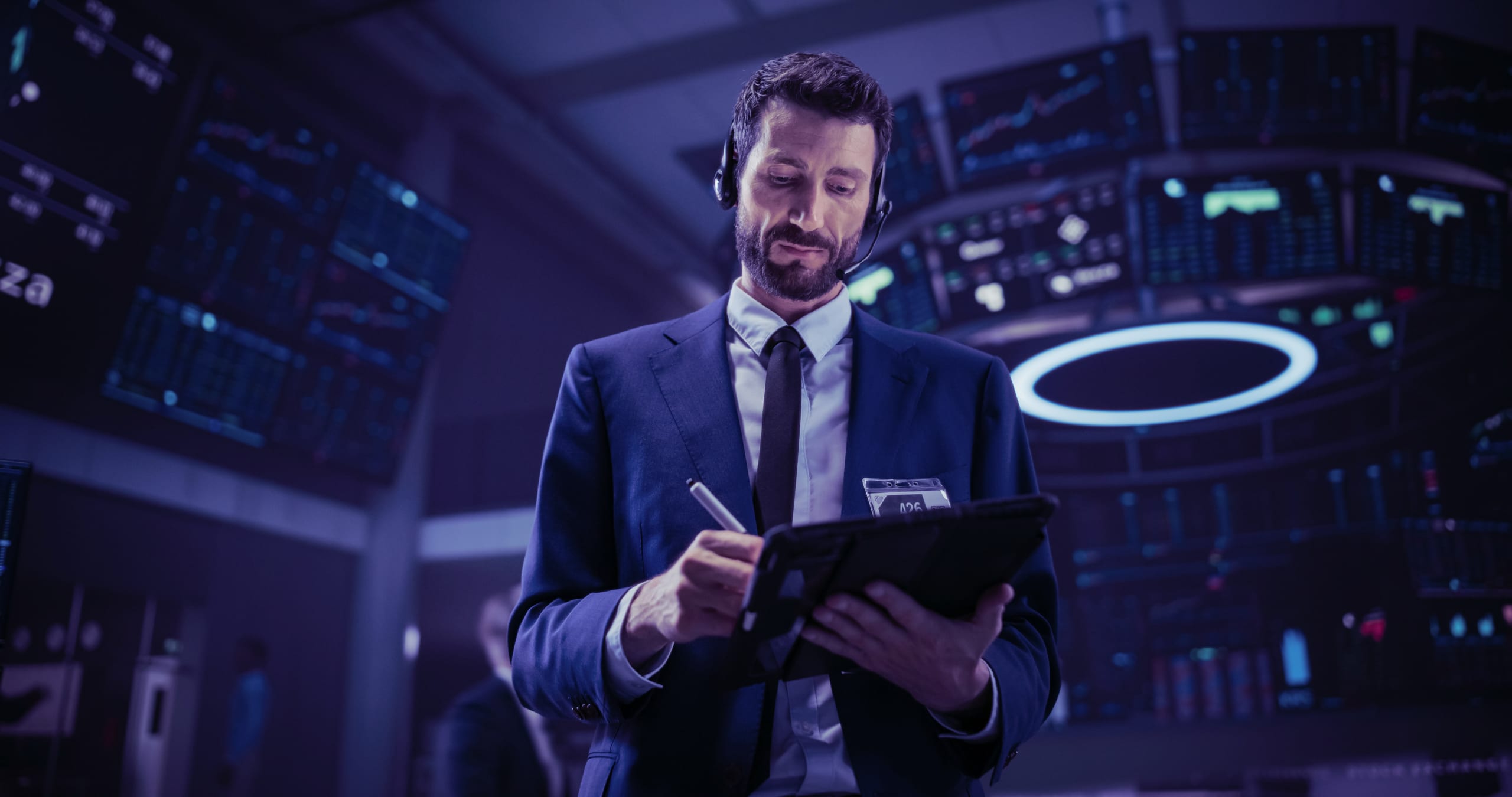 man standing in empty stock exchange with tablet and headset