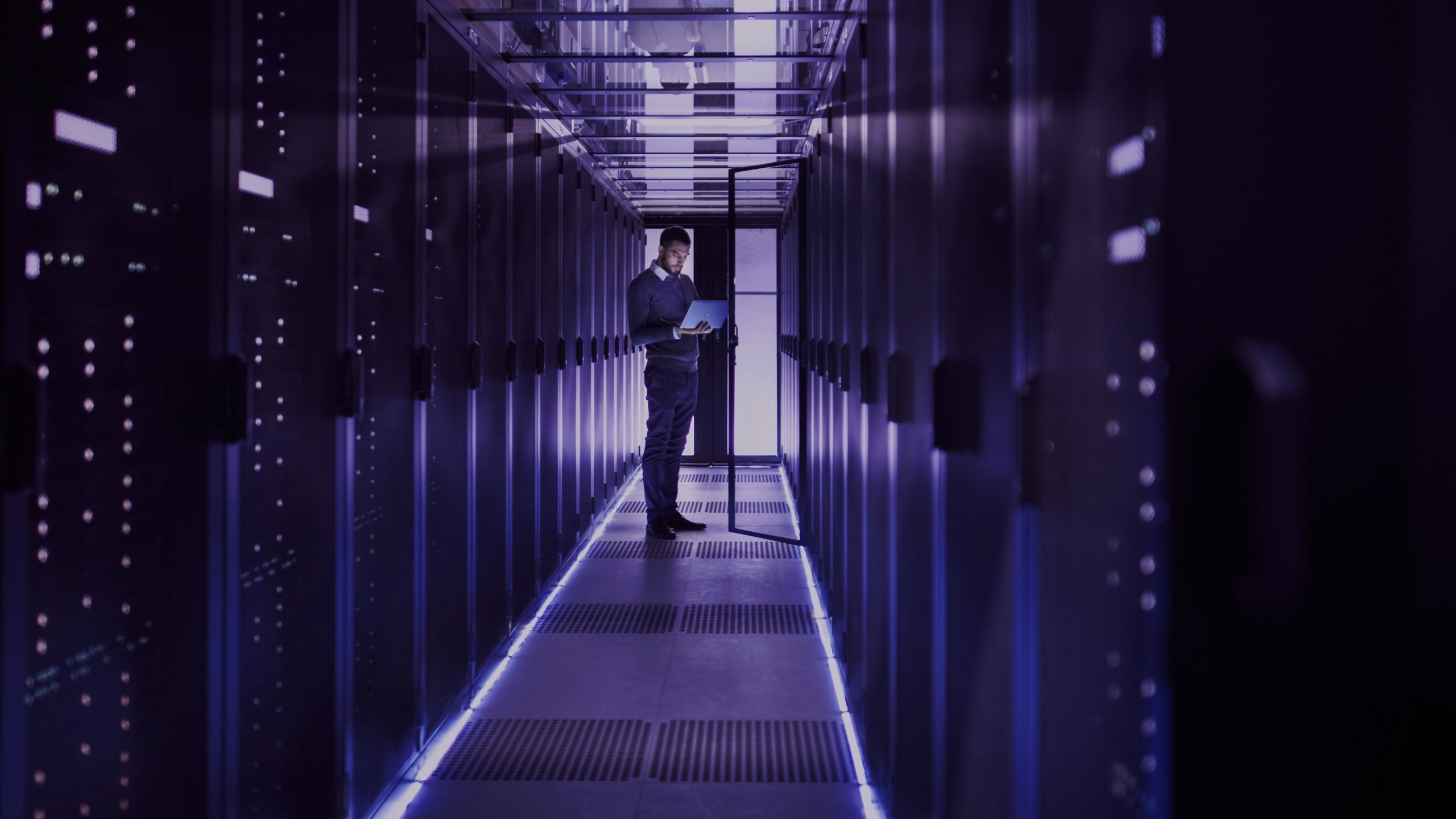 IT technician works on laptop in big data center