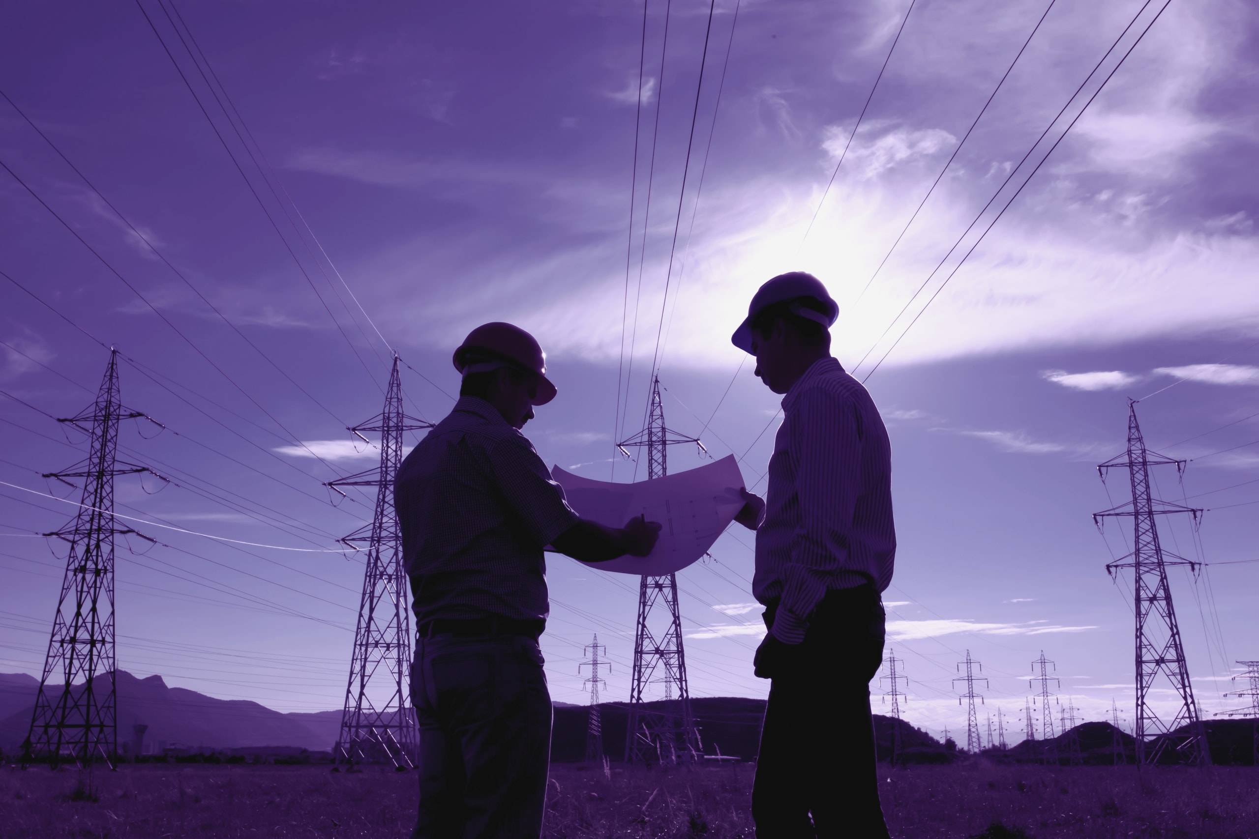 engineers looking at plans under electricity towers