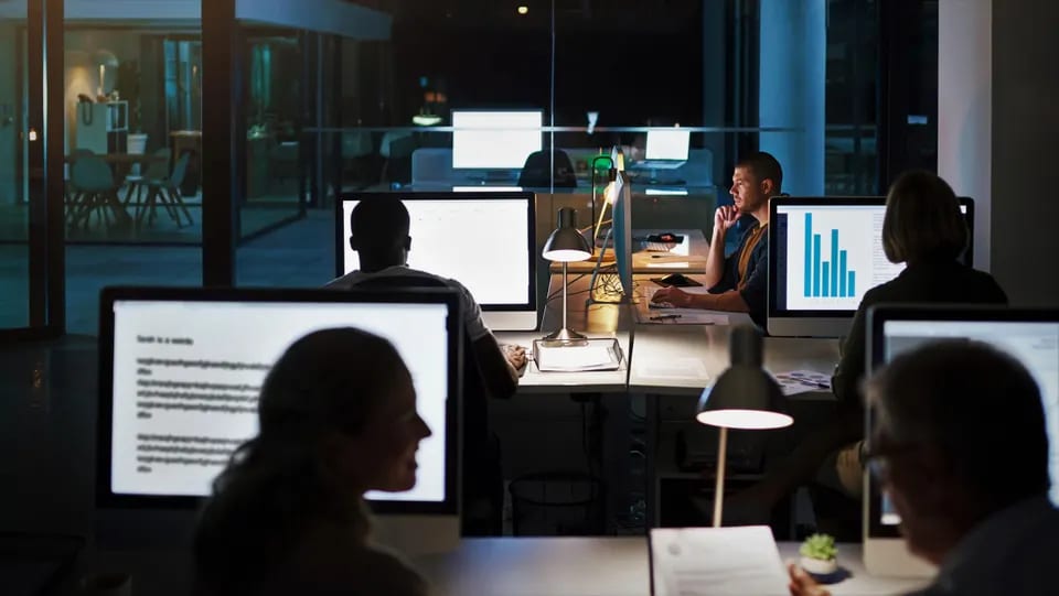 employees in an office at night working at computers