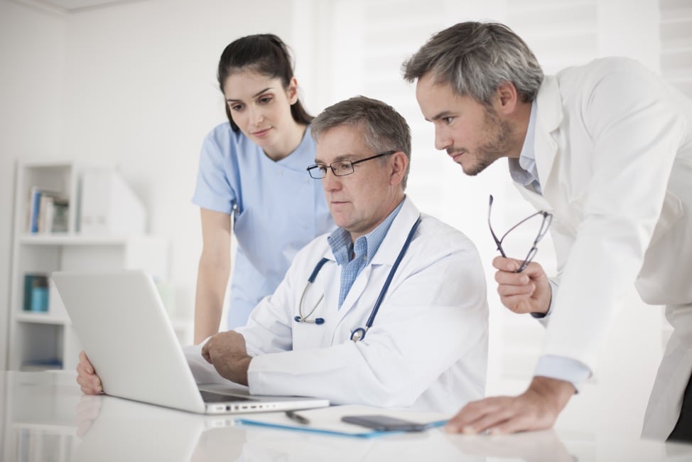 medical team discussing around a computer