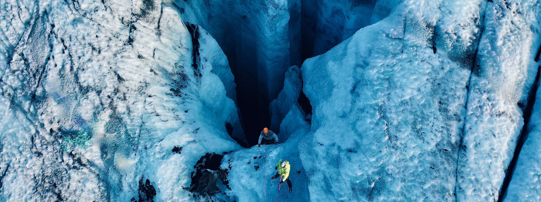 Ice climbers moving through a glacier crevasse system with ropes