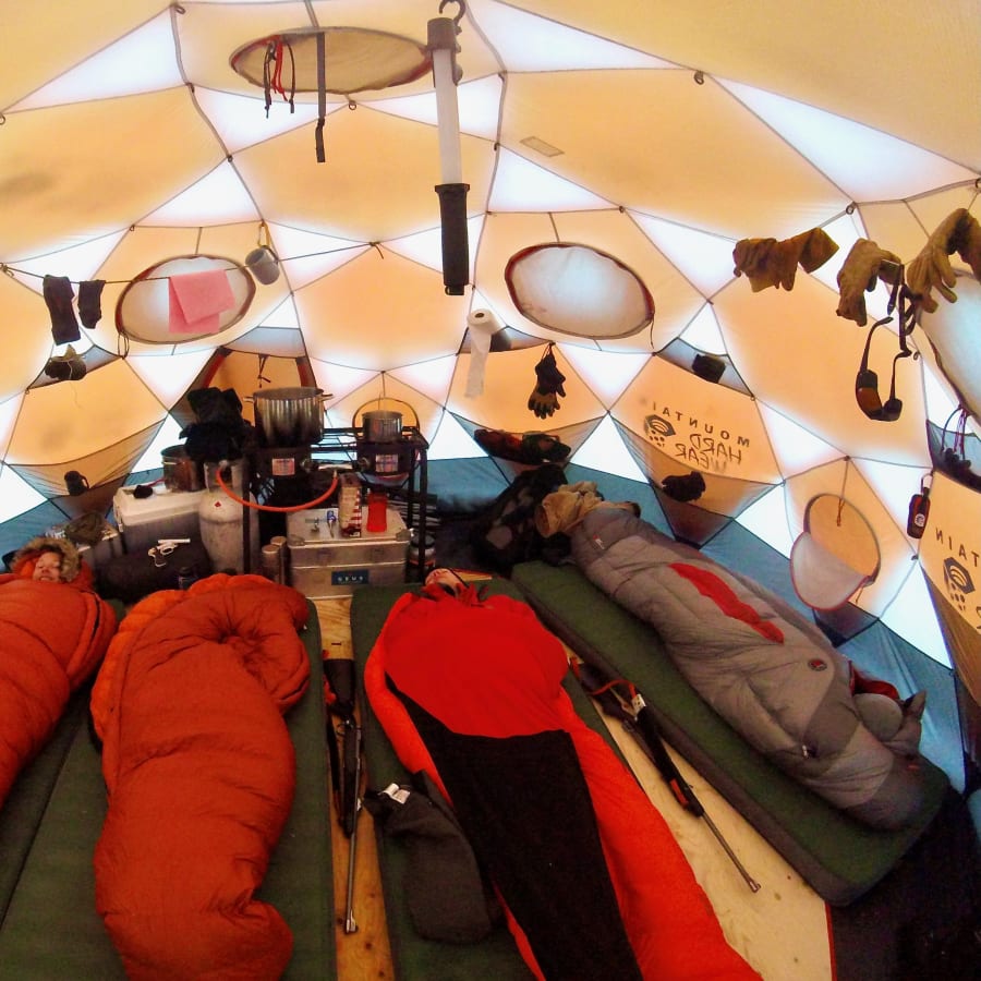 Expedition camp interior with sleeping bags, cooking equipment, and field gear