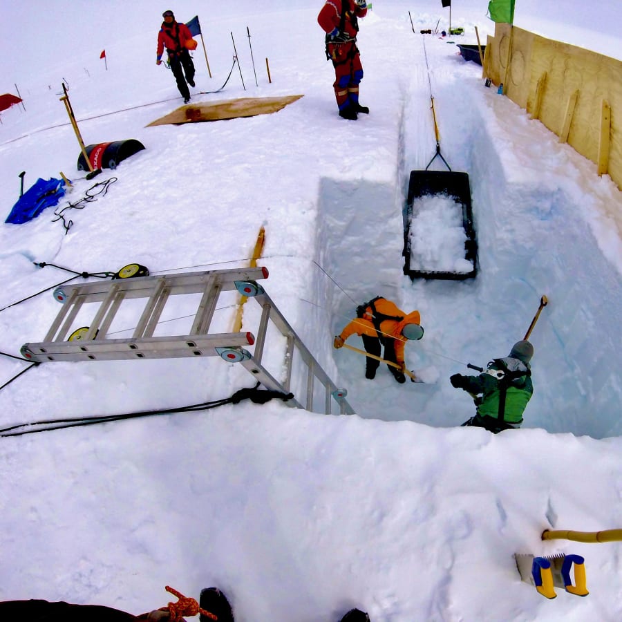 Snow trench field setup with people, equipment, and rescue tools