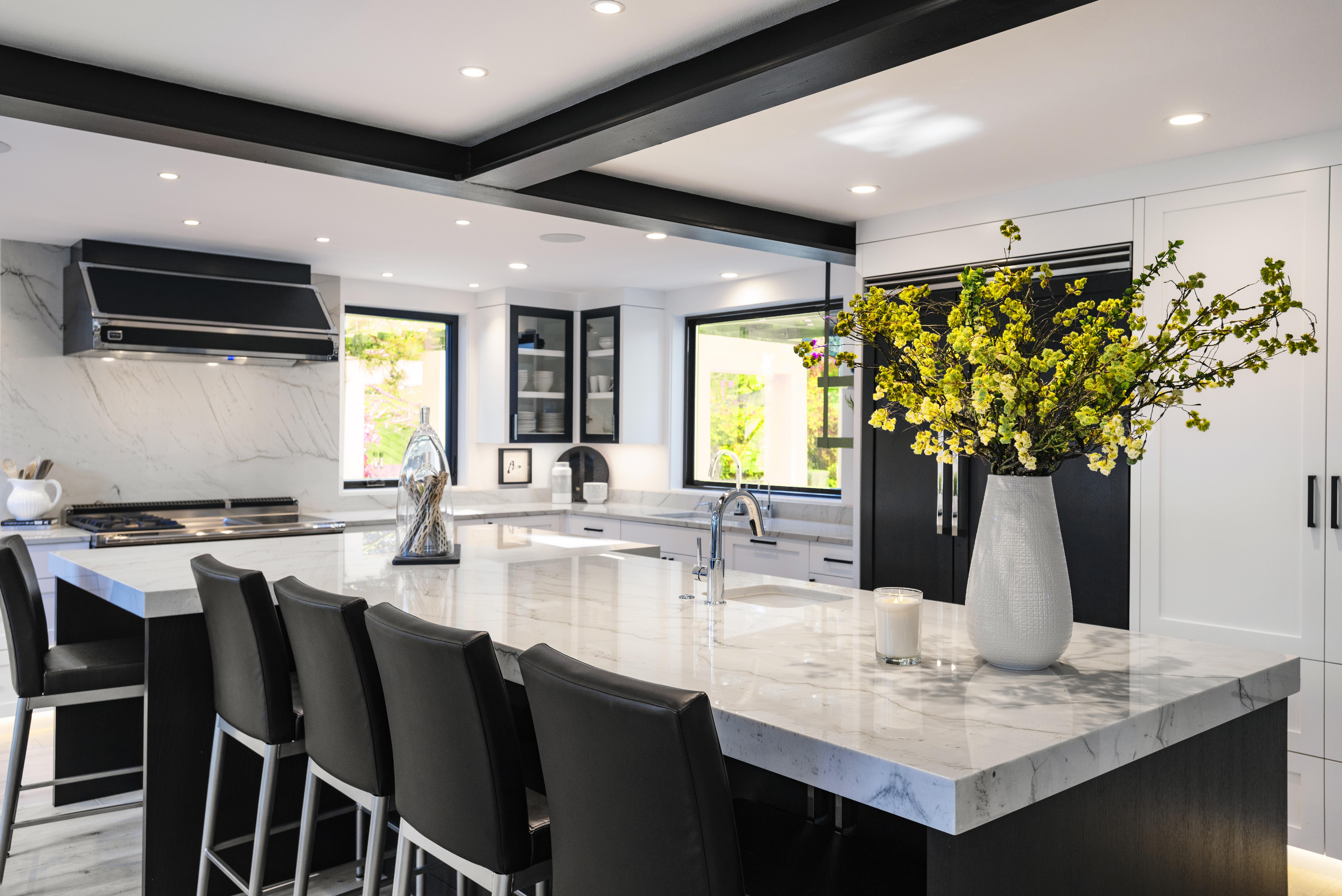 Modern black-and-white kitchen with marble island, waterfall countertops, and seating