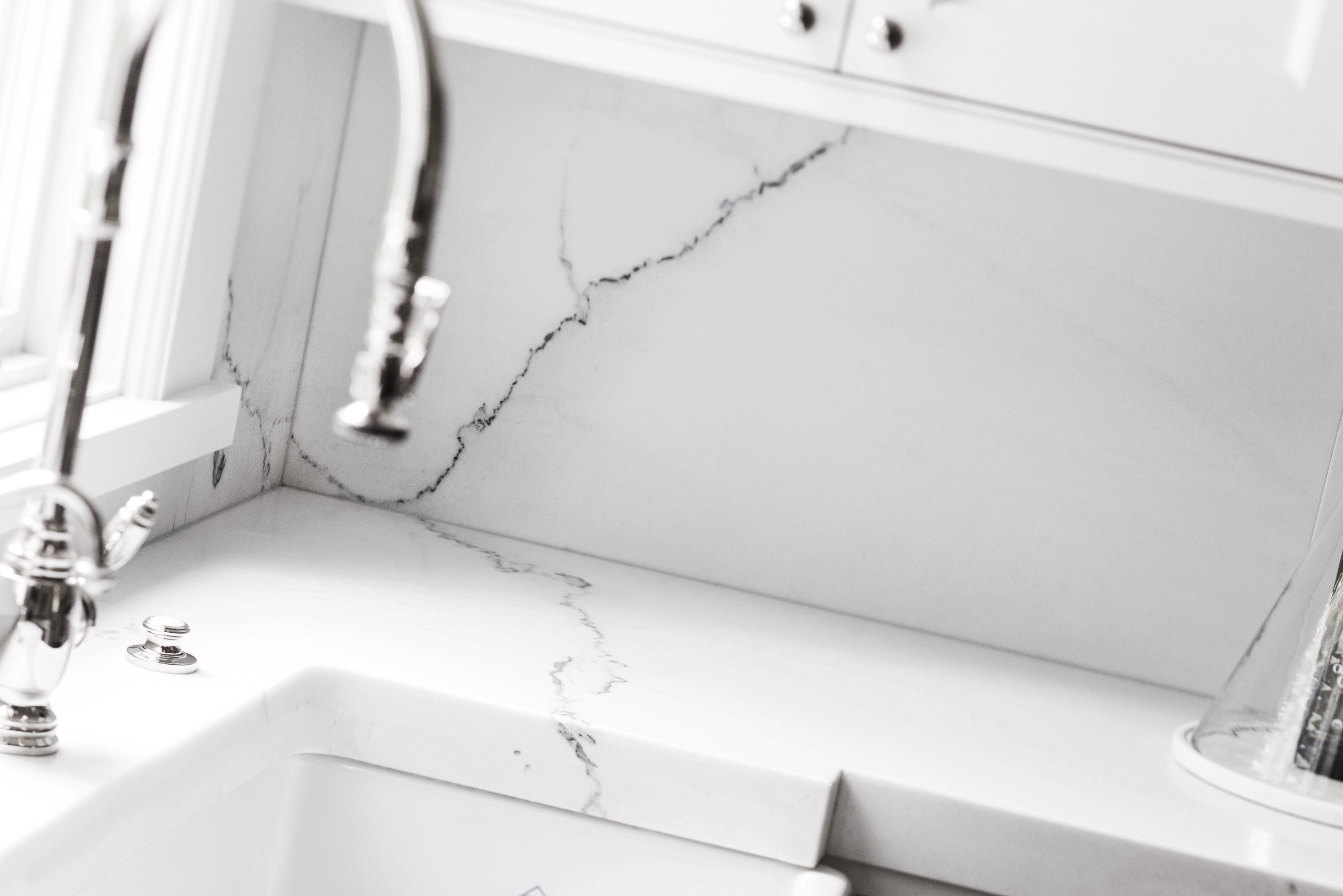 White quartz backsplash and countertop with subtle veining and farmhouse sink