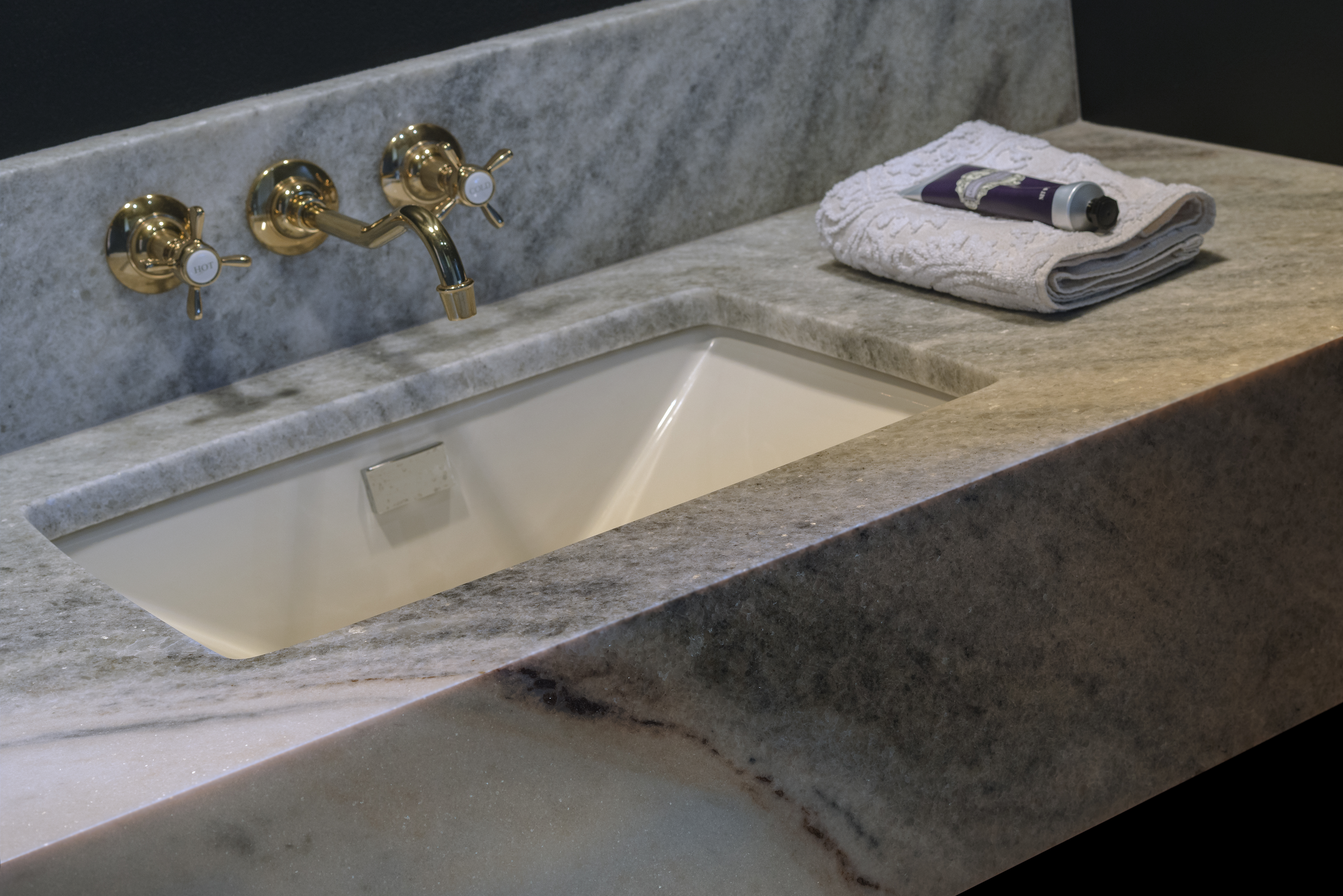 Gray marble vanity countertop with integrated sink and polished brass faucet