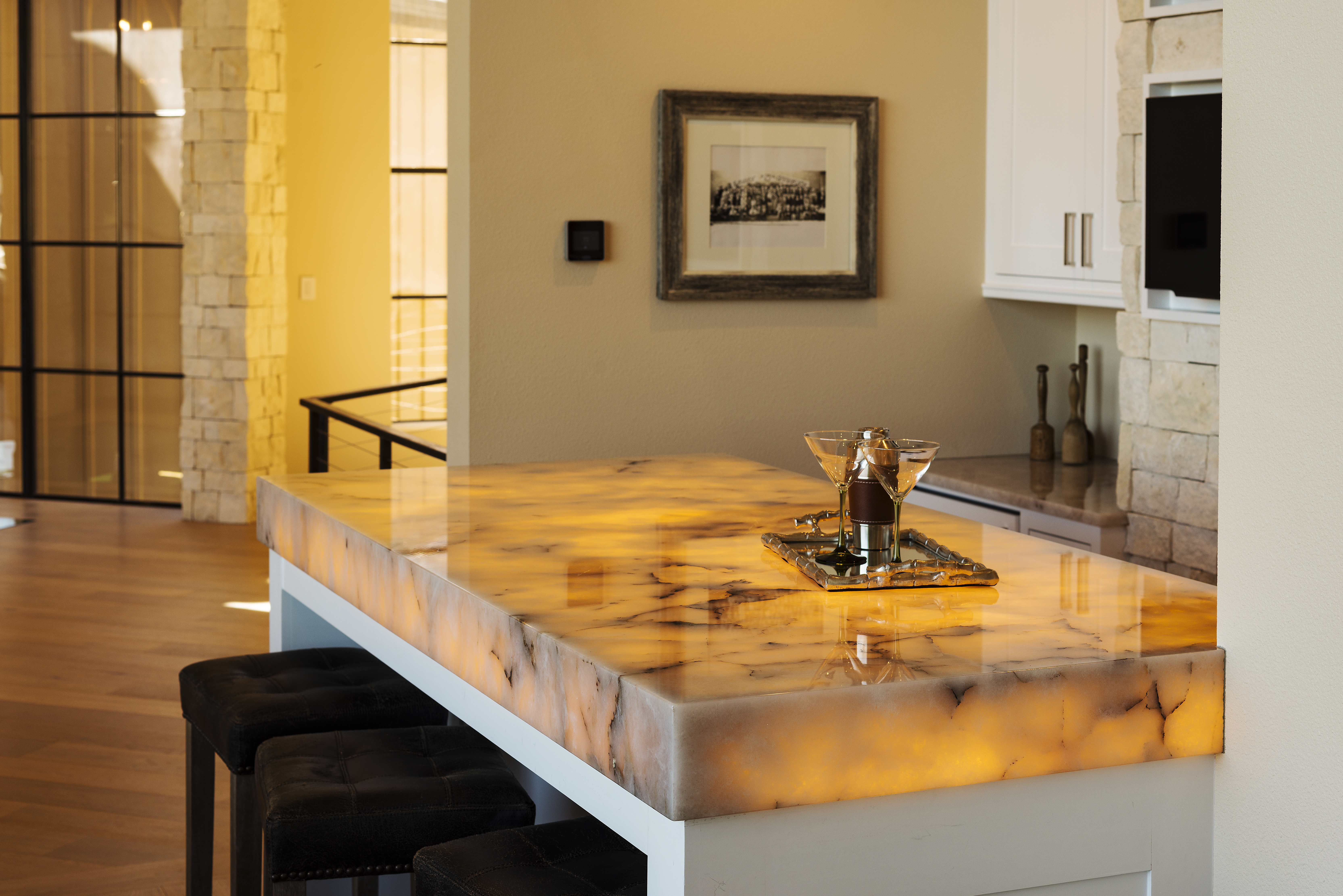 Illuminated stone kitchen island countertop with waterfall edge and bar seating