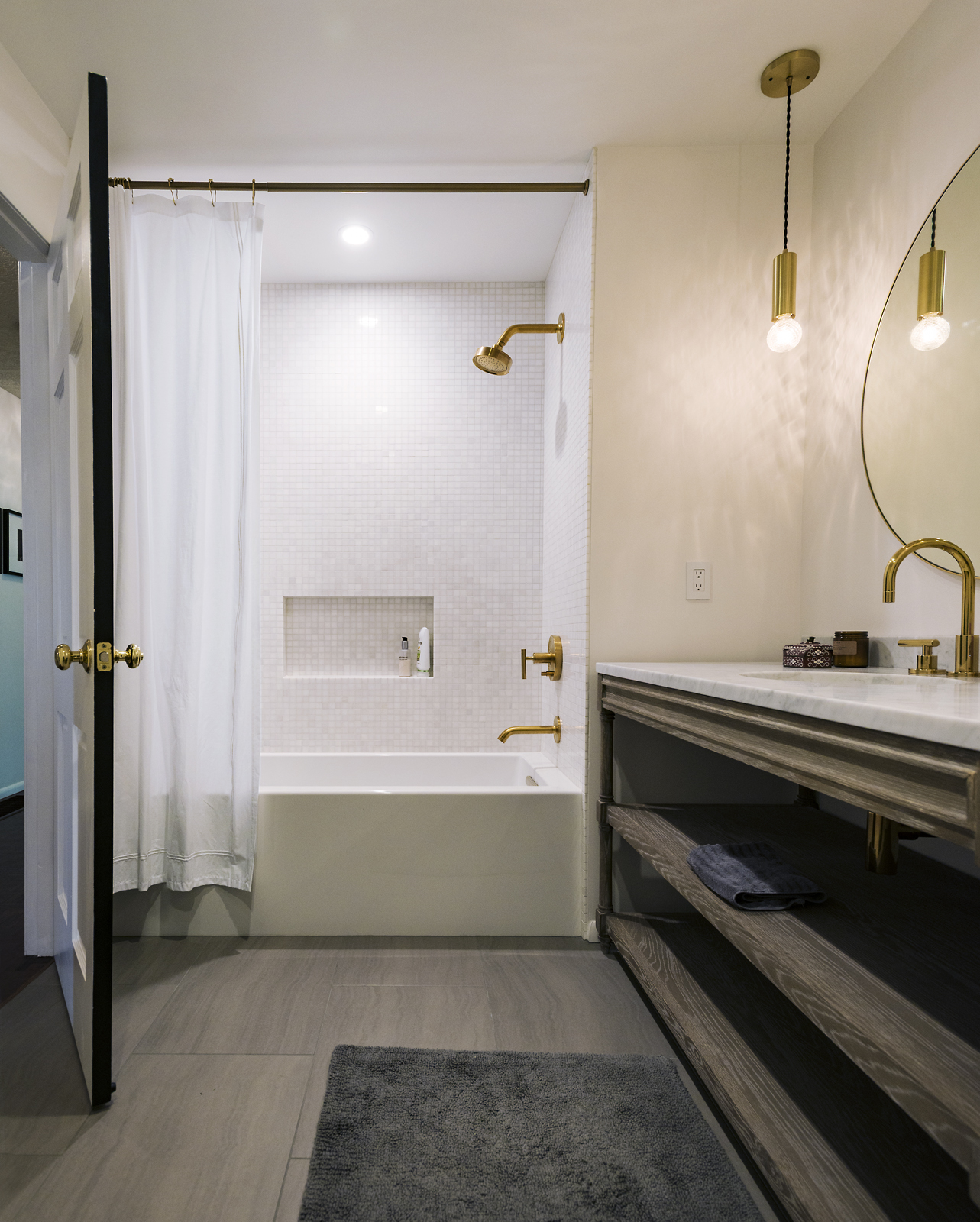 Modern bathroom with gold fixtures, floating vanity, and tub-shower combination