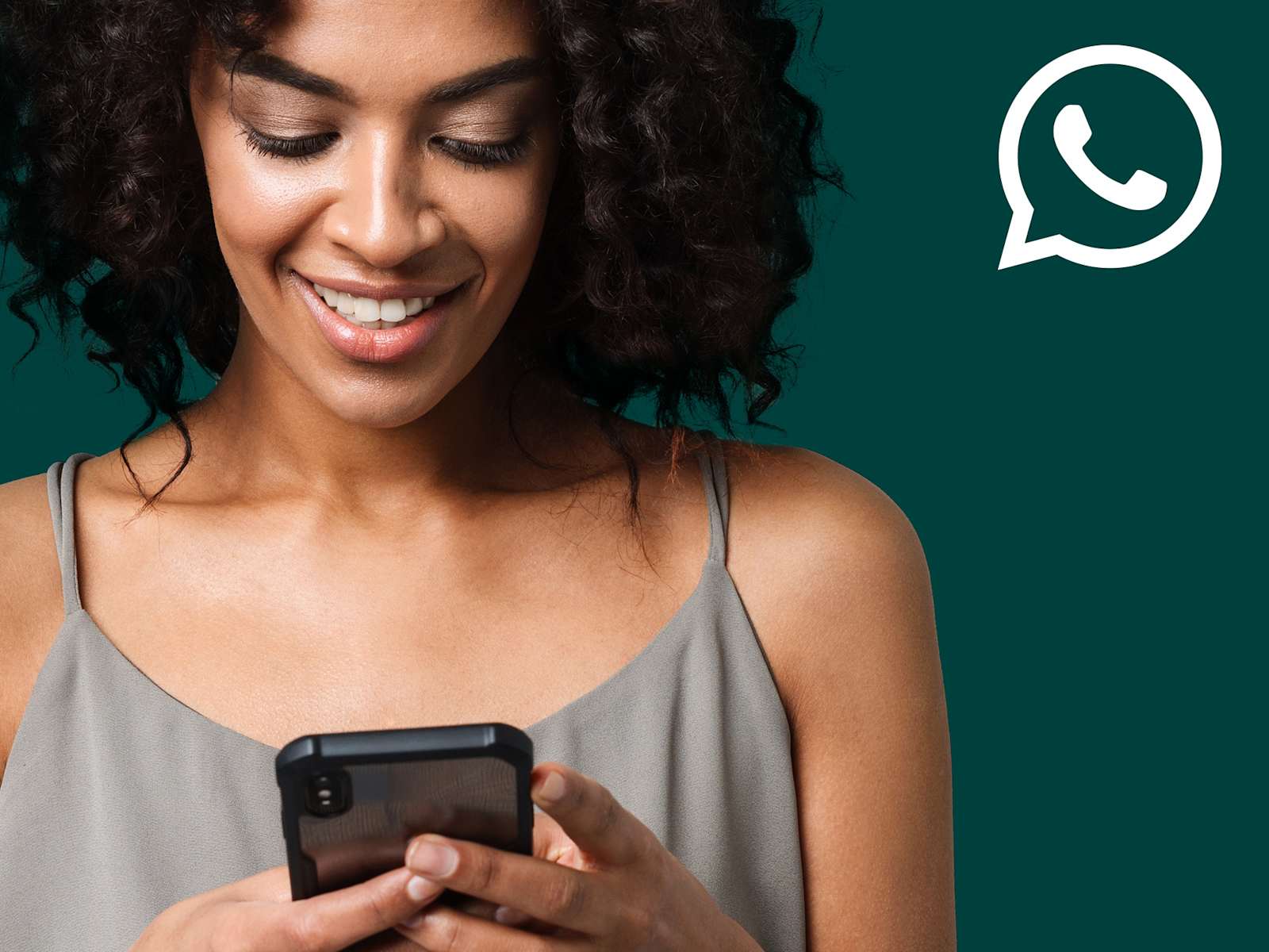 Lachende Frau mit Smartphone in der Hand beim Benutzen von WhatsApp