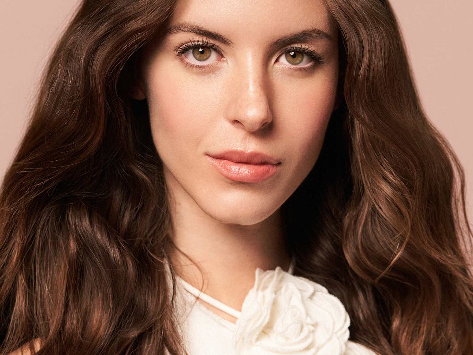 Portrait beauté maquillage naturel, cheveux bruns ondulés, teint uniforme, fond neutre