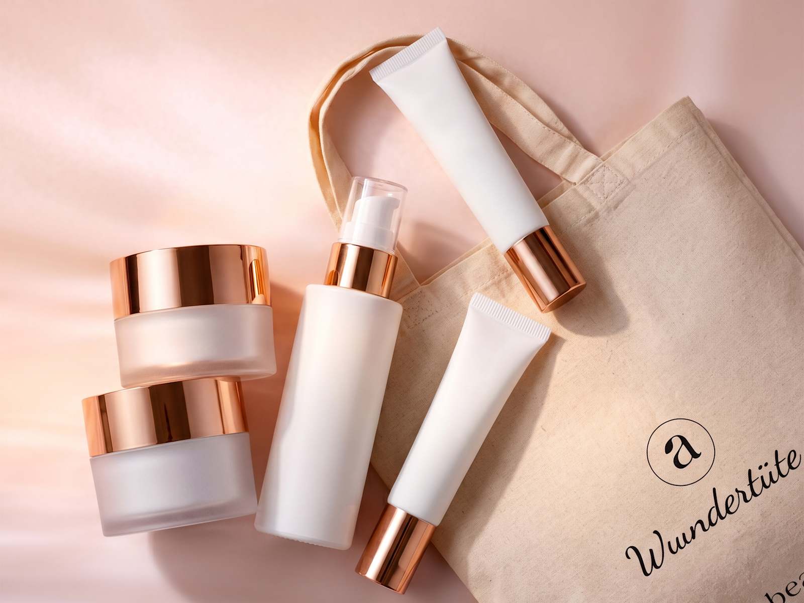 Kosmetikprodukte als Produktbild neben Stoffbeutel mit roségoldenen Verschlüssen