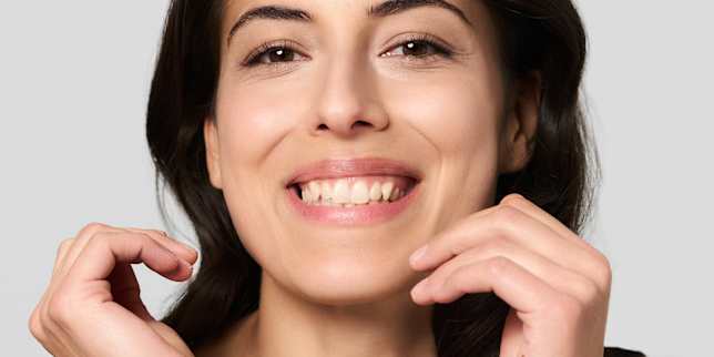Portrait beauté d’une femme souriante au maquillage naturel et cheveux foncés