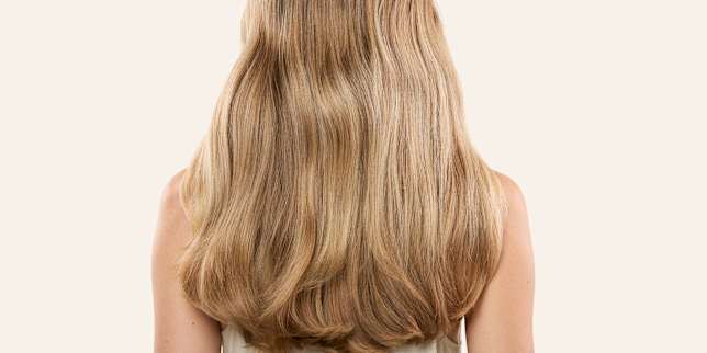 Beauty-Porträt mit langem, welligem blondem Haar von hinten