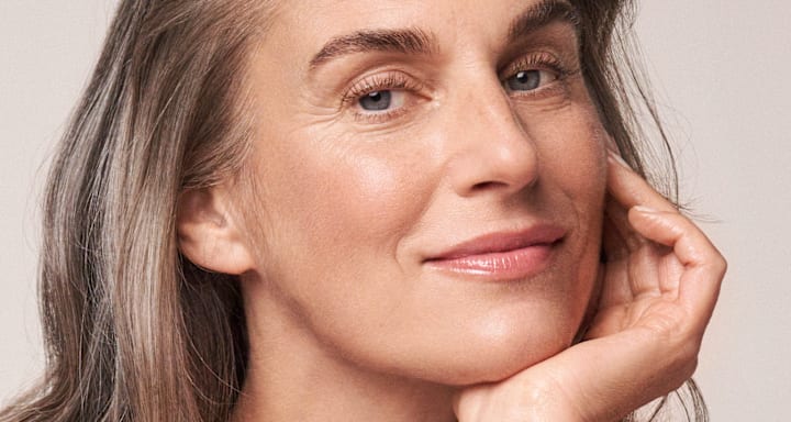 Frau blickt nach der Anwendung der hautstraffenden RESVERATROL PREMIUM NT50 Produkte entspannt in die Kamera.
