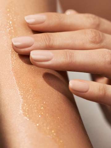 Anwendung Körperöl auf Haut mit schimmernder Textur und Hand