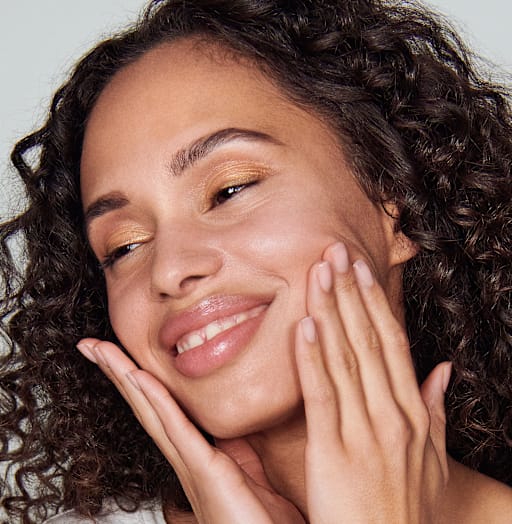 Une femme se tient satisfaite, après avoir appliqué les produits de soin AQUA INTENSE, les mains posées sur ses joues.