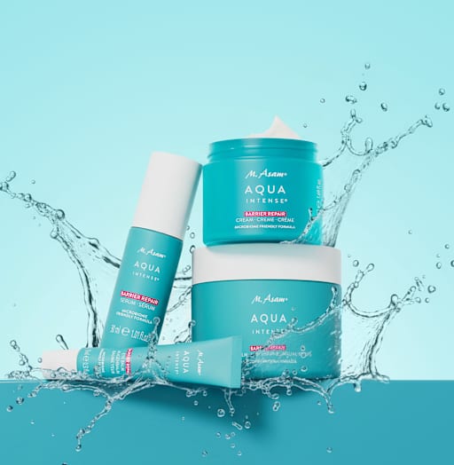 Gesichtsserum, Augenbalsam, Gesichtscreme und Körperbalsam von M. Asam AQUA INTENSE Barrier Repair in türkisfarbenen Verpackungen mit Wasser-Splash-Effekt.