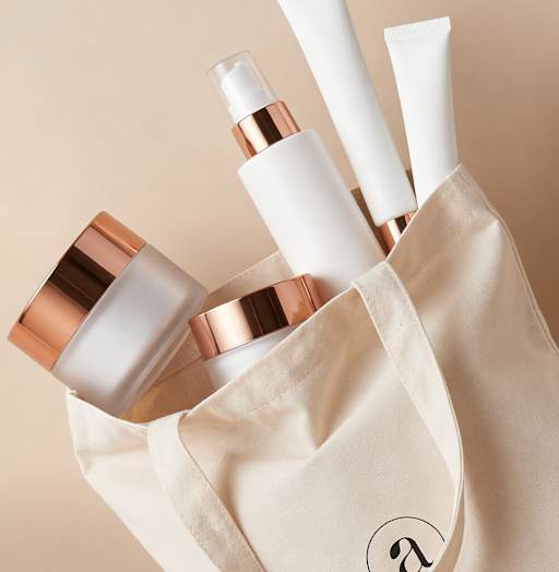 Kosmetikflaschen im Beutel als Produktbild mit roségoldenen Verschlüssen