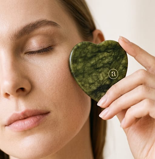 Beauty-Porträt mit geschlossenem Auge und herzförmigem grünen Gesichtsmassage-Stein