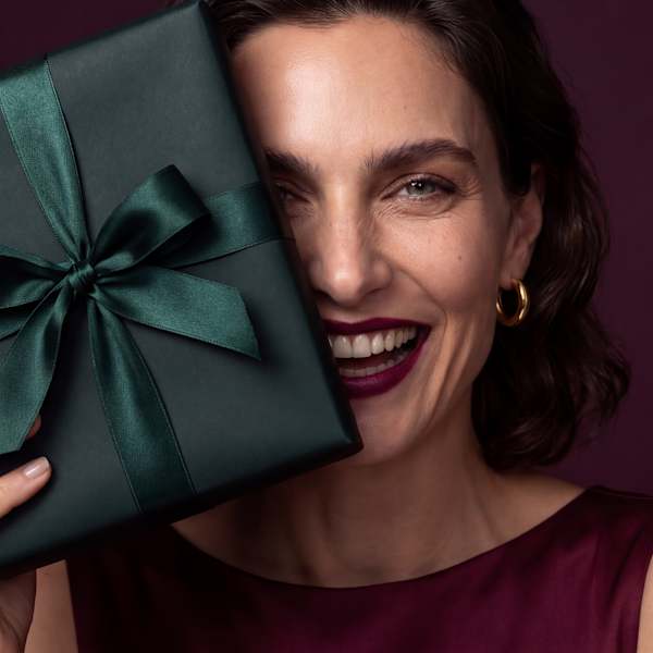 Beauty-Porträt einer lächelnden Frau mit dunkelgrünem Geschenkpaket