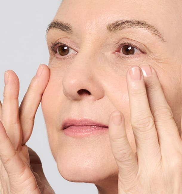 Frau cremt sich mit einer Gesichtscreme von M.Asam ein