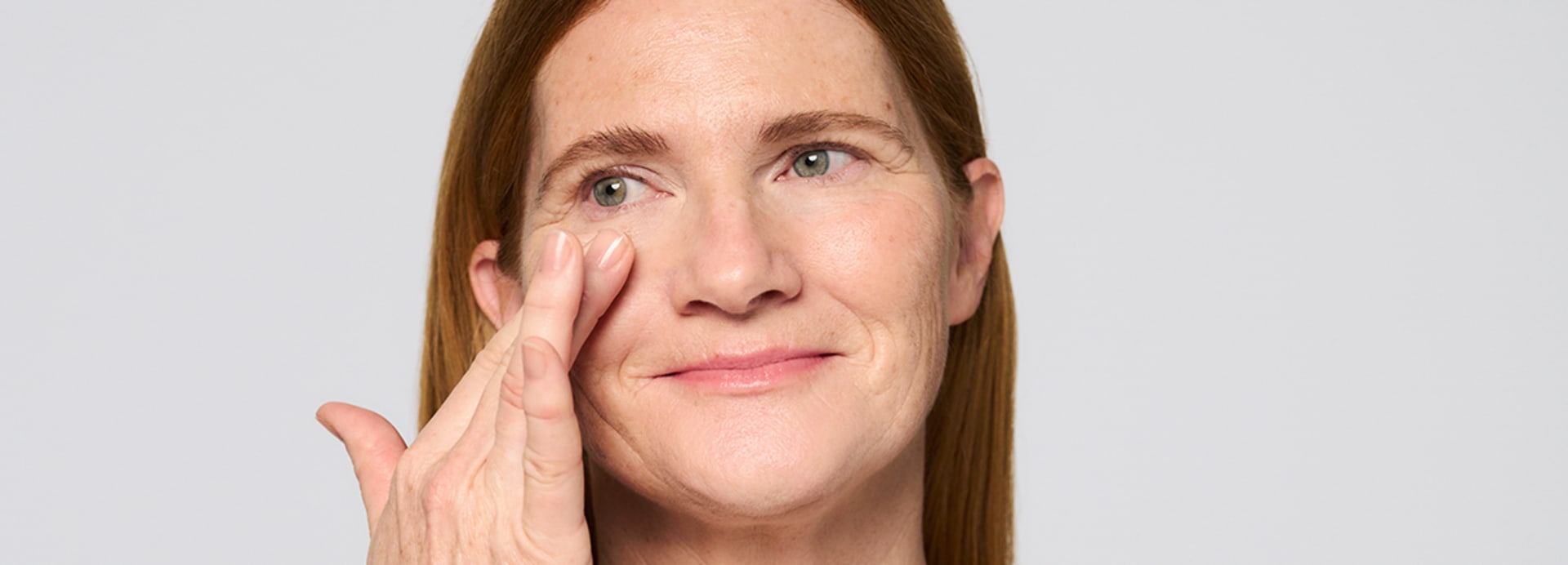 Frau trägt Vitamin E Gesichtscreme von M.Asam mit den Fingern auf die Wange auf