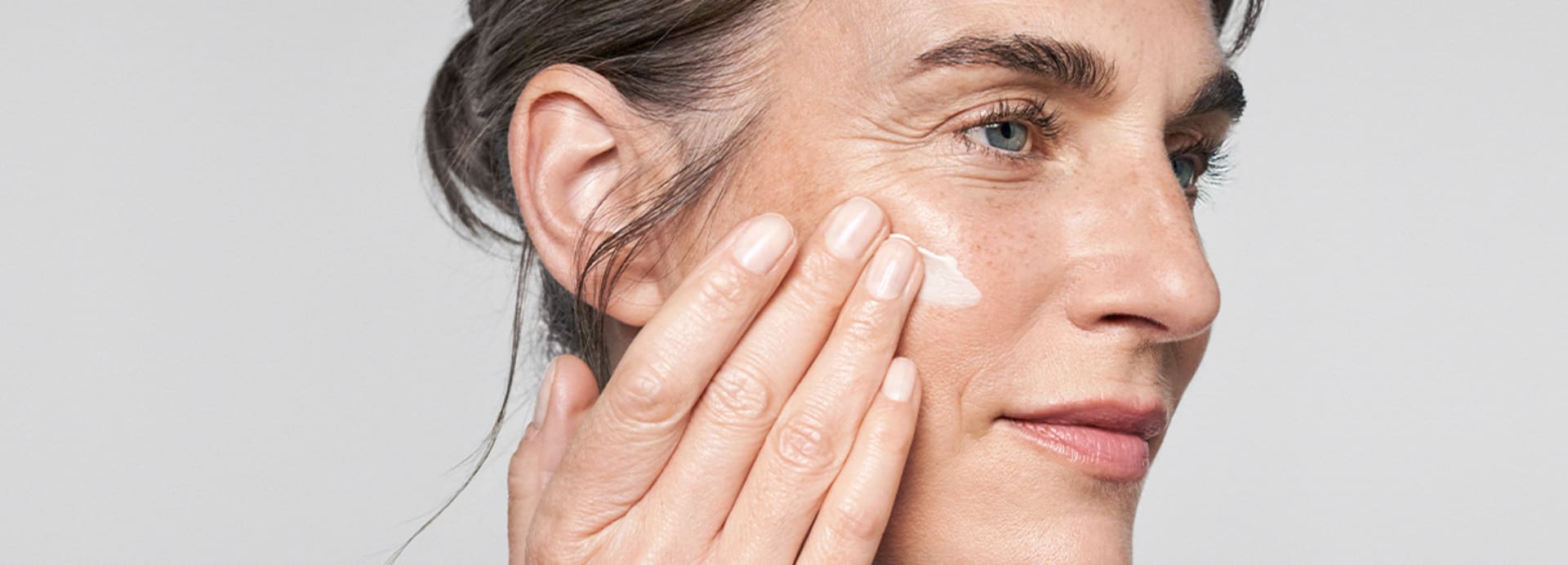 Frau trägt die straffende RESVERATROL PREMIUM NT50 Lifting Creme von M. Asam auf die Wange auf – aus seitlicher Perspektive.