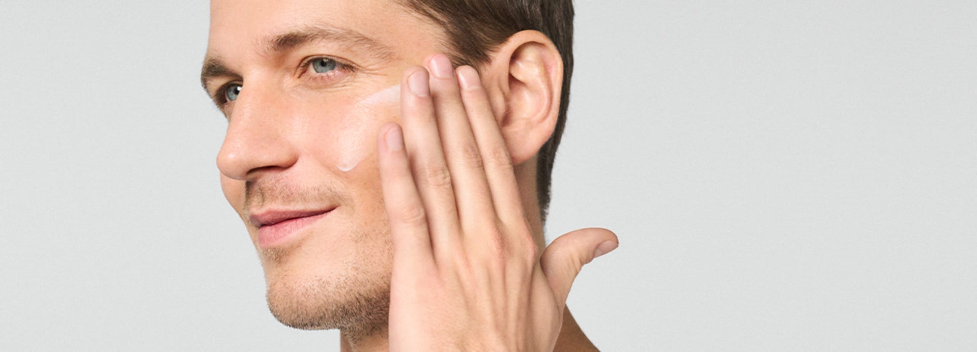 Un homme applique la crème suprême HYDRATATION INTENSE au hyaluron sur son visage avec les mains.