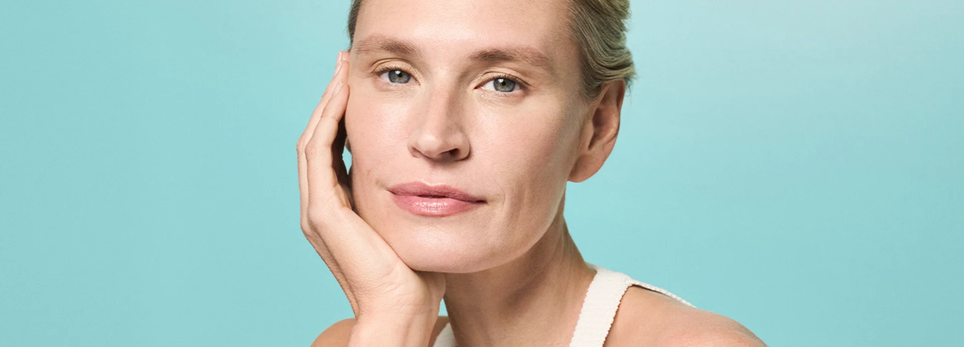 Femme regardant l’objectif avec satisfaction après l’application des soins AQUA INTENSE – visuel de campagne mettant en avant une peau éclatante et soignée.