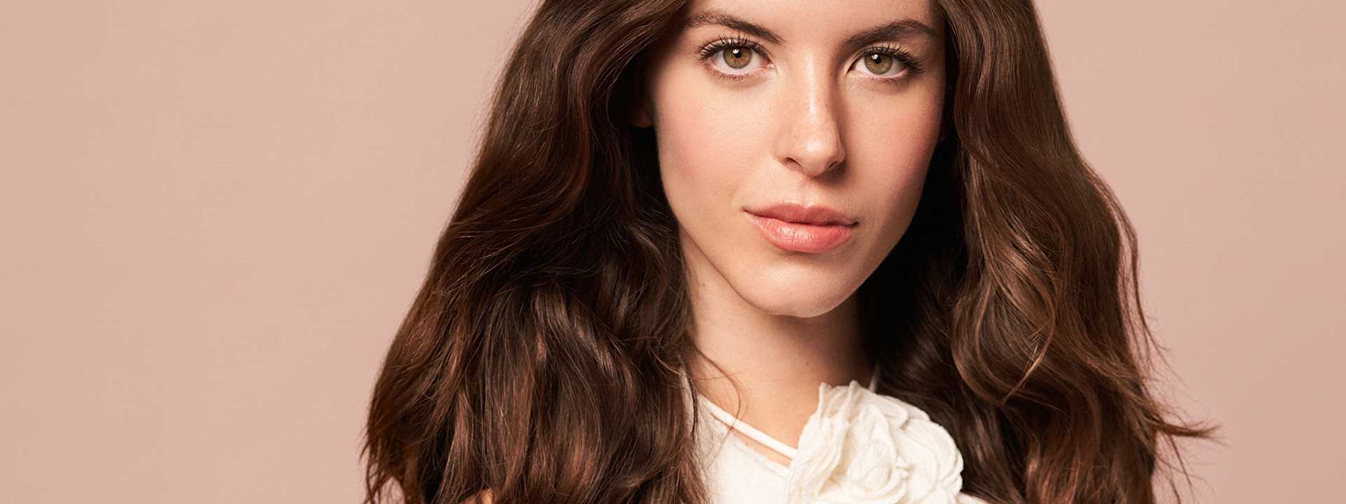 Portrait beauté maquillage naturel, cheveux bruns ondulés, teint uniforme, fond neutre