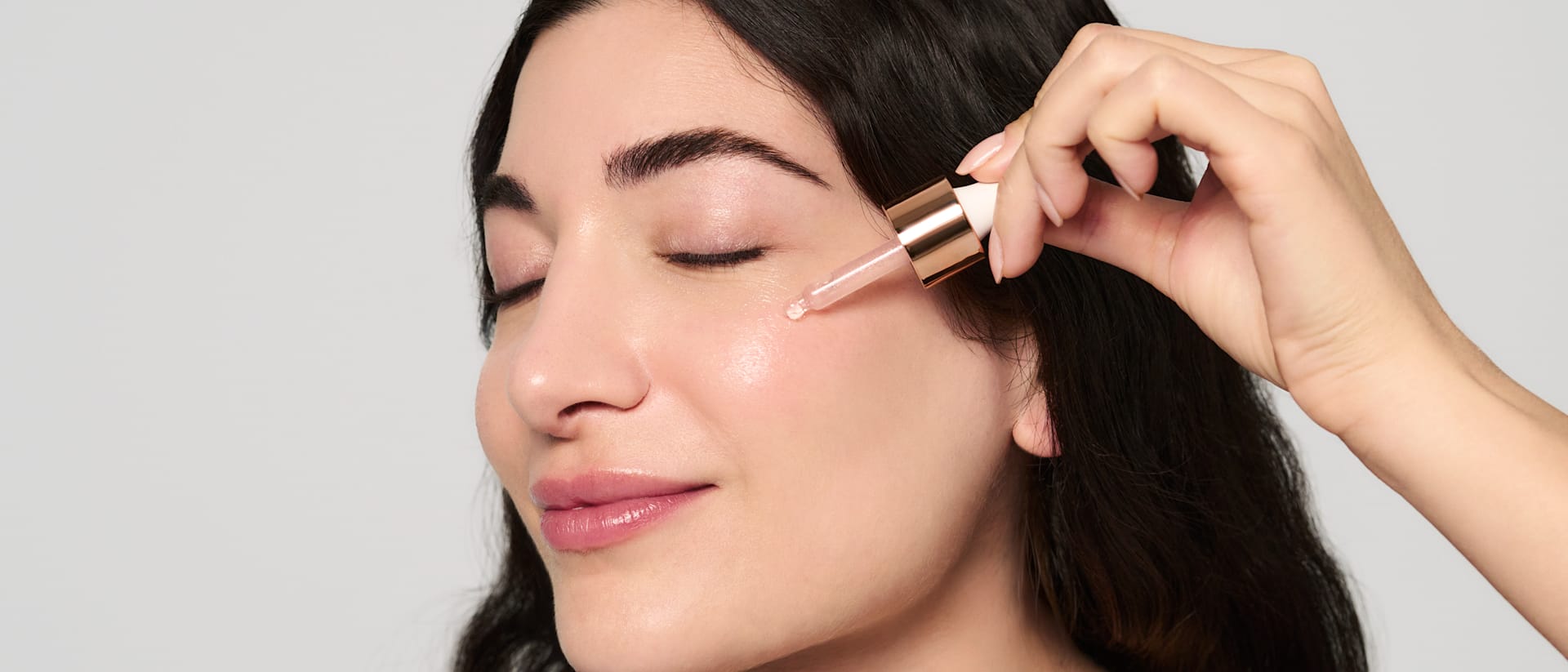 Frau trägt ein Gesichtsserum von M. Asam mit dem integrierten Applikator auf die Wange auf