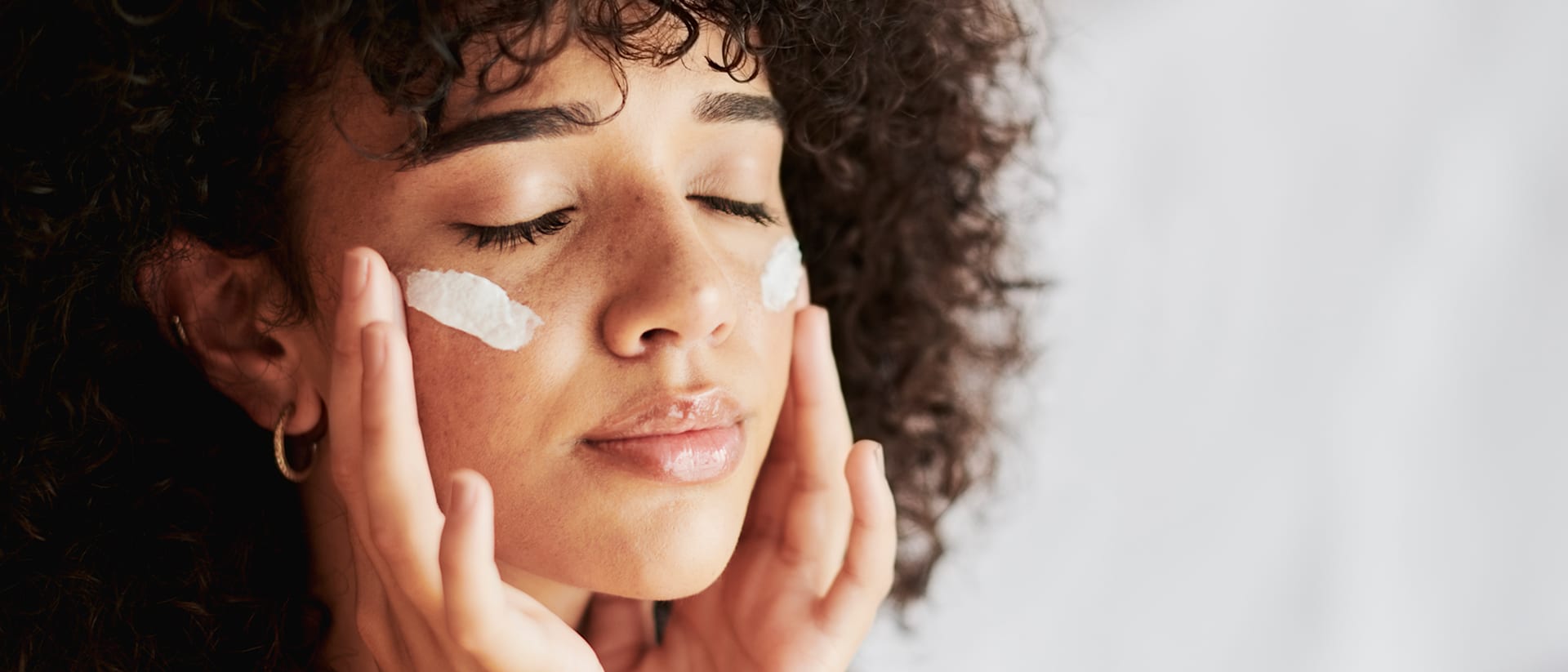 Frau trägt eine Gesichtscreme von M. Asam mit den Fingern auf die Wangen auf