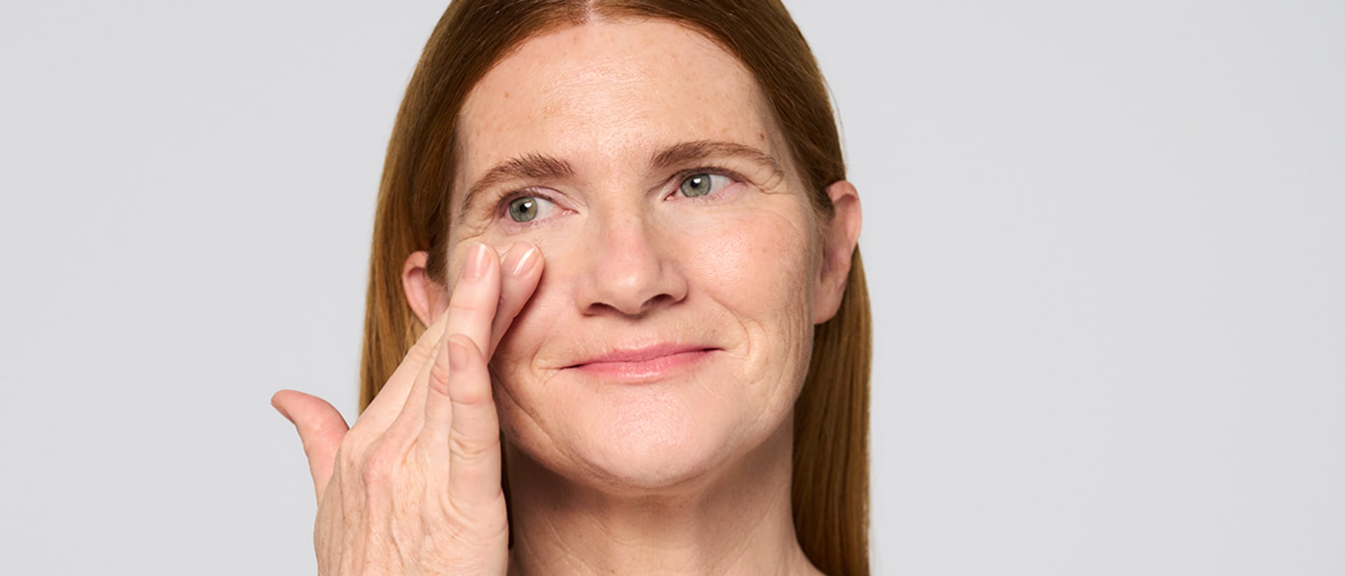 Frau trägt Vitamin E Gesichtscreme von M.Asam mit den Fingern auf die Wange auf