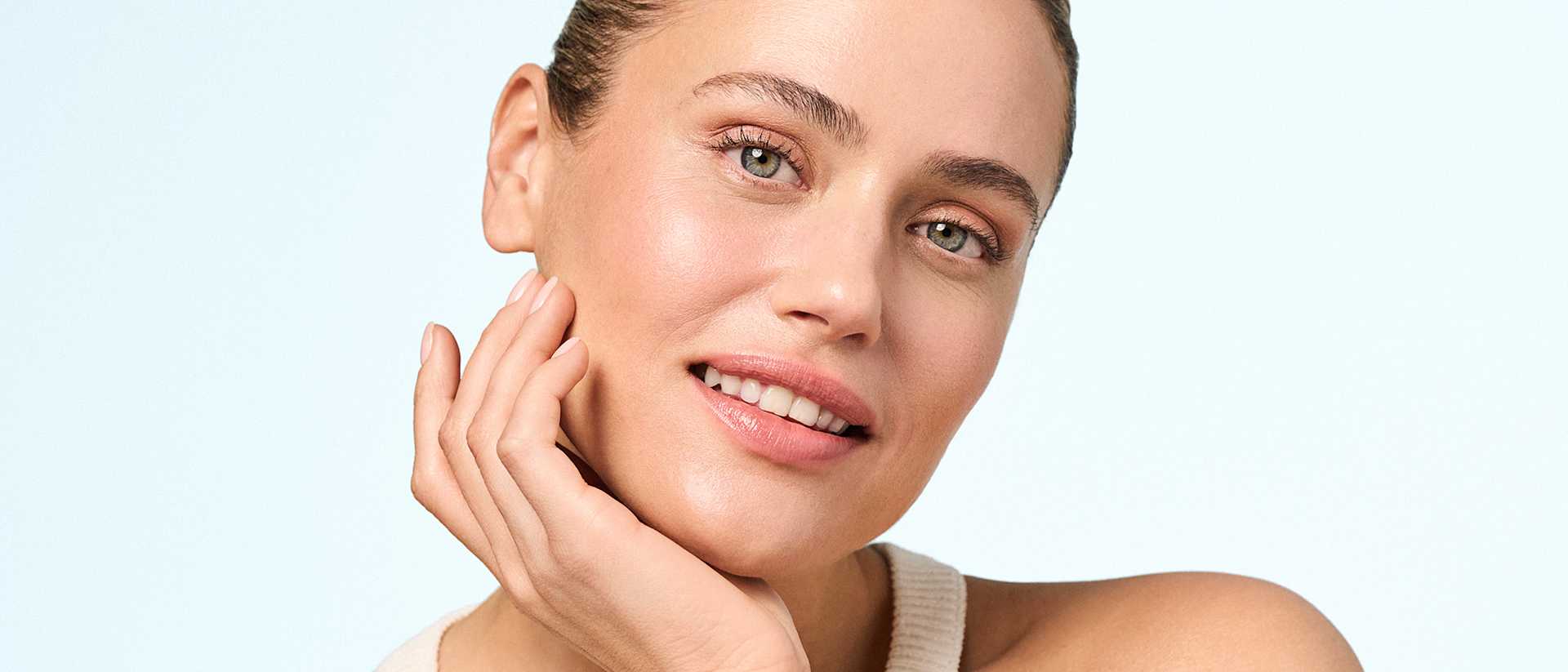 Portrait beauté femme maquillage naturel, main sur joue, teint éclatant