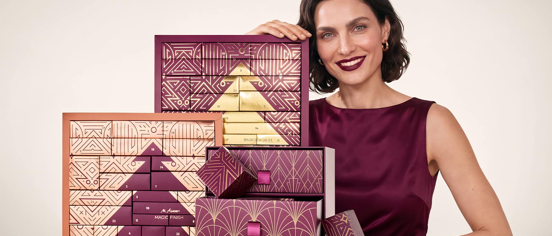Beauty-Porträt mit Frau in Burgunderrot neben dekorativen Geschenkboxen