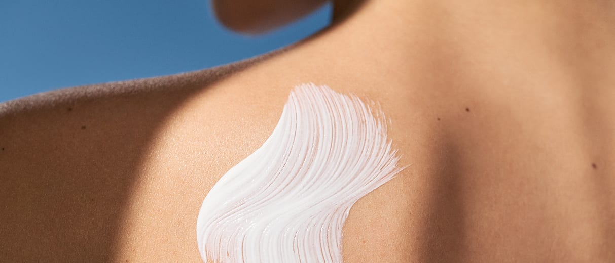Frau hat Sonnencreme von M.Asam auf dem Rücken aufgetragen