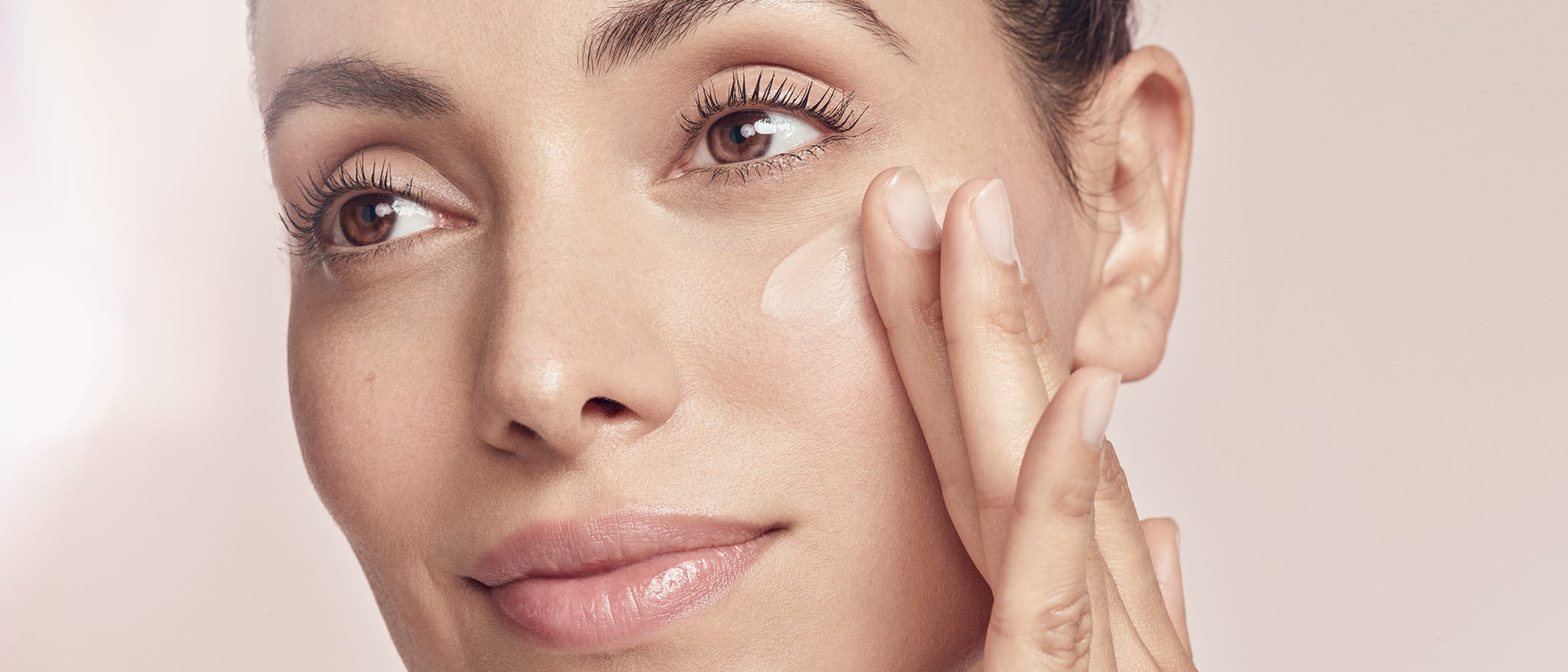 Frau trägt die Magic Care Glow up Gesichtcreme von M.Asam mit den Fingern auf ihre Wangen auf