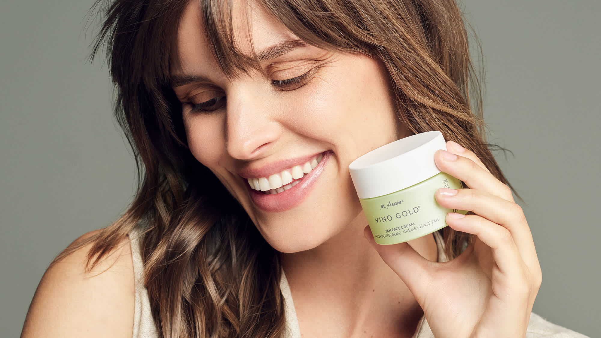 Frau im Beauty-Porträt mit VINO GOLD Cremetiegel von M. Asam nahe am Gesicht