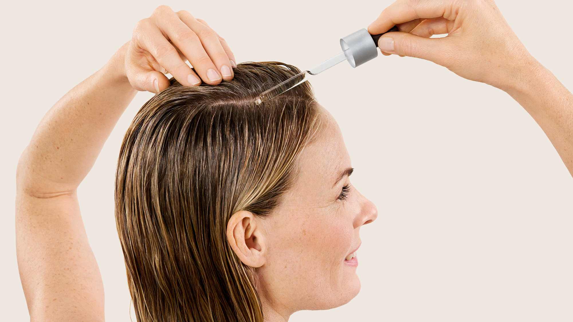 Anwendung von Haarserum mit Pipette auf der Kopfhaut, nasses Haar wird gekämmt
