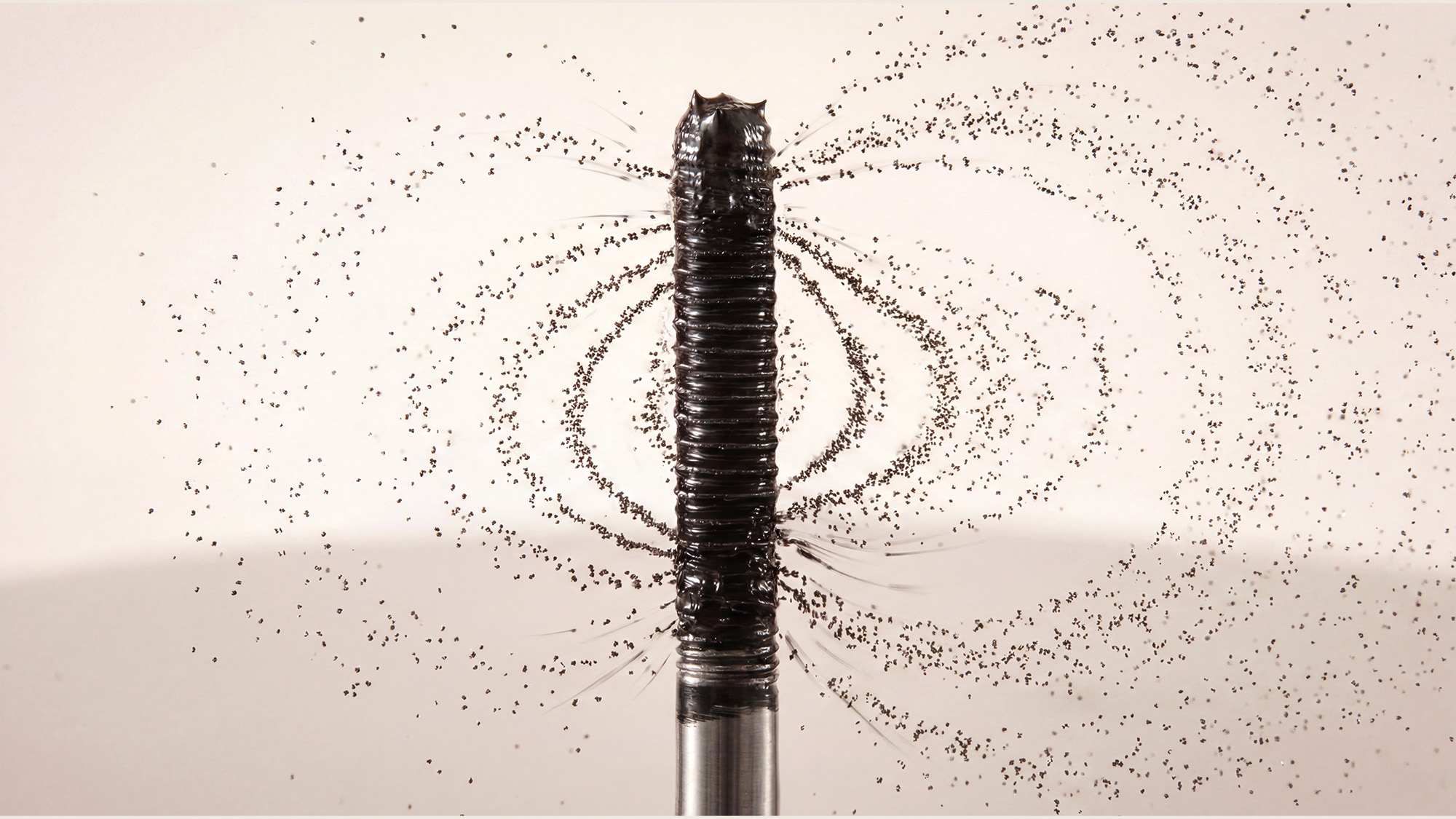 Detailaufnahme einer schwarzen Mascara-Bürste mit feinen Produktpartikeln