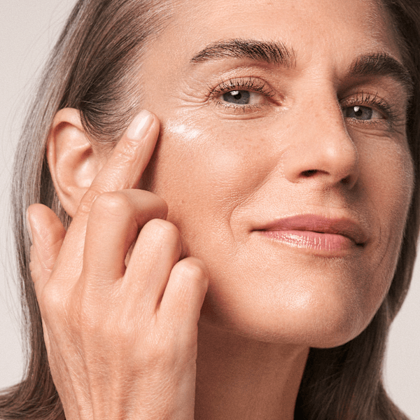 La femme applique la crème contour des yeux perfectionnante RESVERATROL PREMIUM NT50 de M. Asam sur la zone de ses yeux.