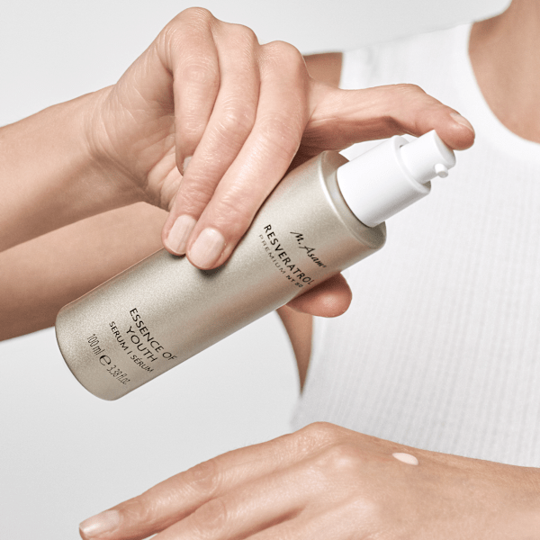 Frau trägt das RESVERATROL PREMIUM NT50 Essence of Youth Serum mit dem Pumpspender auf ihren Handrücken auf.