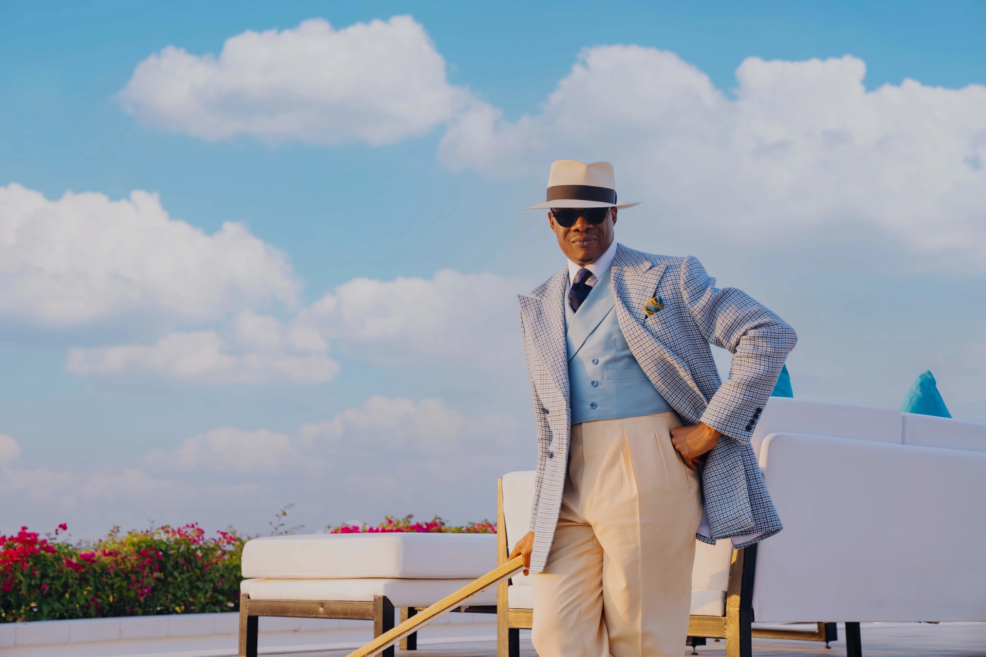 Man in a pale checked jacket and powder-blue waistcoat on a sunlit terrace