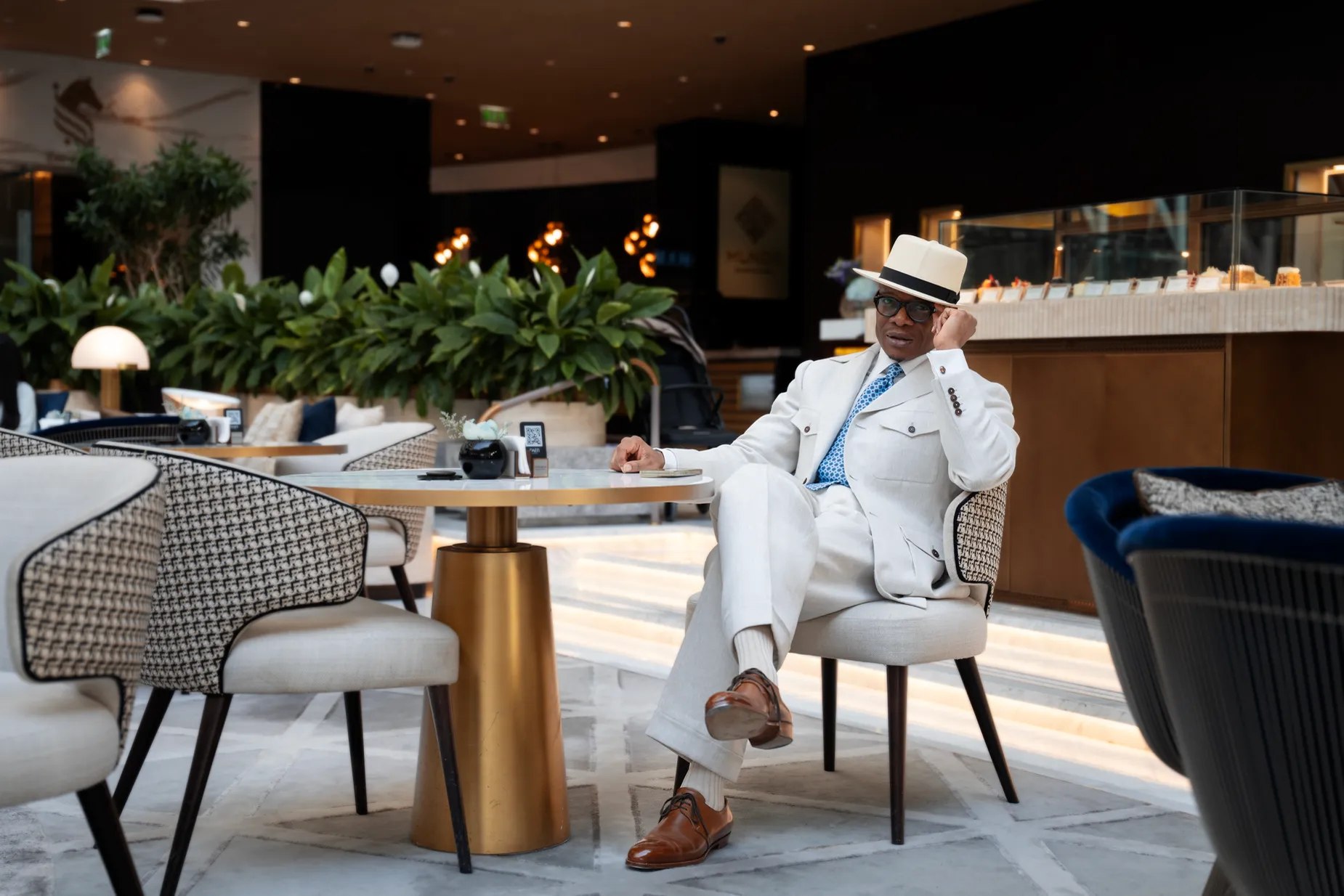 Man in a white suit seated in a hotel lounge